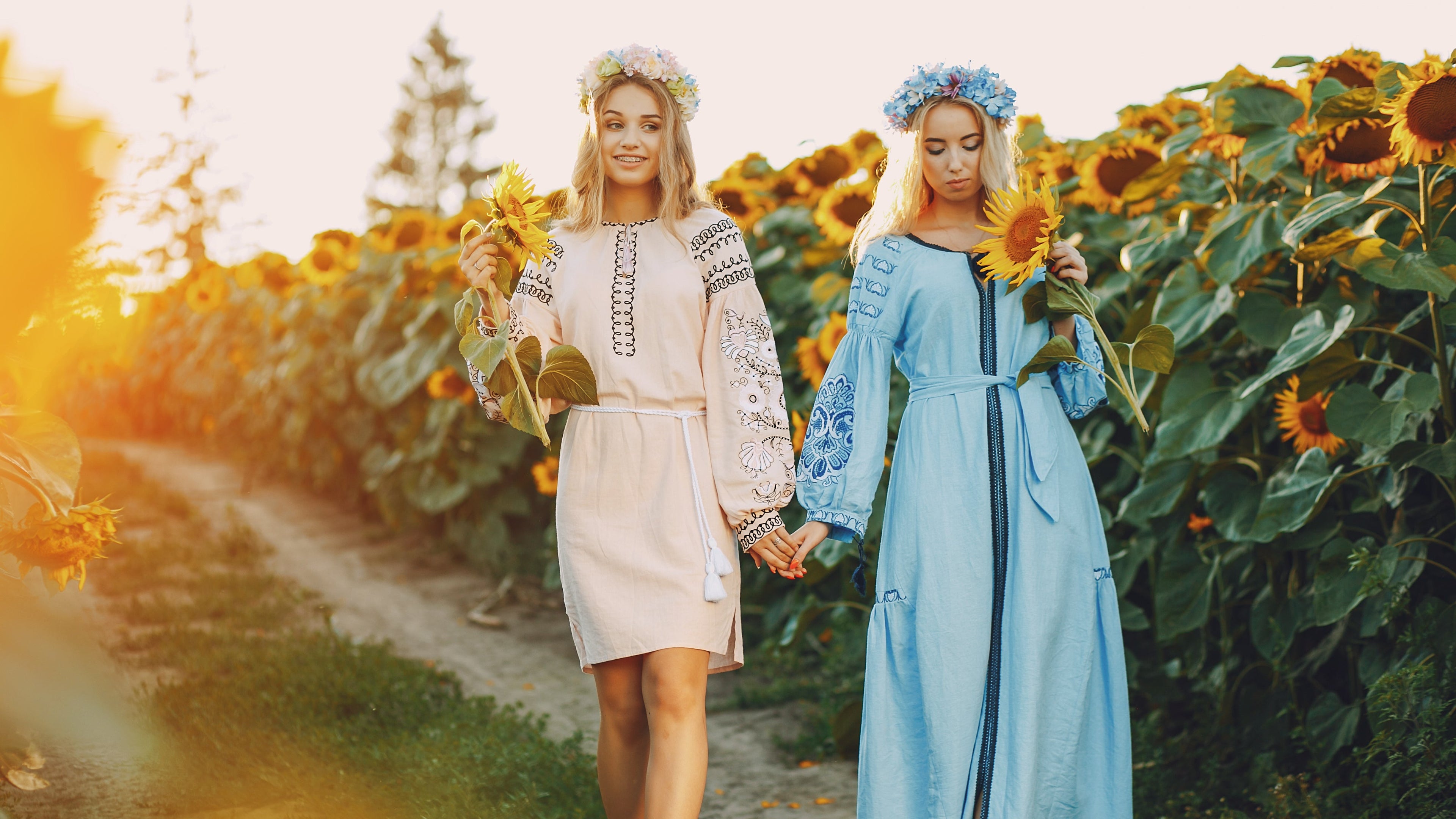 Two women holding hands in a sunflower field